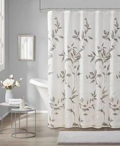 a white bath tub sitting next to a shower curtain in a bathroom with gray walls