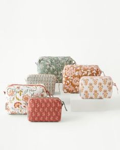 six small cosmetic bags lined up on top of each other in various colors and patterns