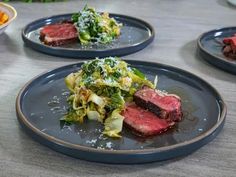 three plates with steak, broccoli and other food items on them sitting on a table