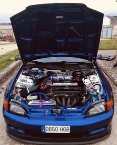 a blue car with its hood open and the engine in it's trunk is shown