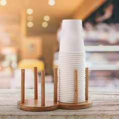 a stack of white cups sitting on top of a wooden stand next to each other