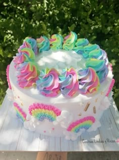 a cake with rainbow frosting and sprinkles sitting on top of a wooden table