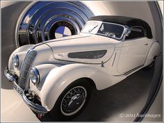 an old white car is parked in front of a large blue object