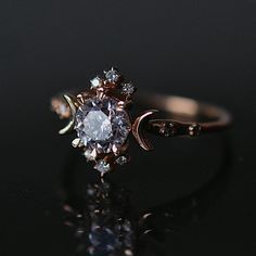 a close up view of a ring on a black surface with the moon and stars in it