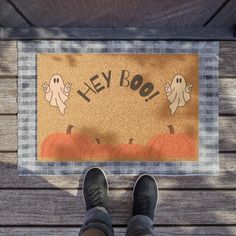 someone standing in front of a door mat that says hey boo with ghost on it