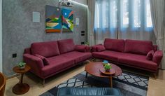 a living room with two couches, a coffee table and paintings on the wall