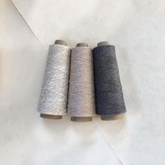 three spools of yarn sitting next to each other on a white tablecloth