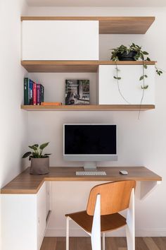 a desk with a computer, books and plants on the top shelf in front of it