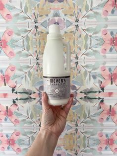 a hand holding a bottle of milk in front of a wallpapered background that says never's