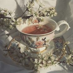 a tea cup and saucer sitting on top of a plate with flowers in it