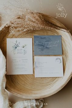 the wedding stationery is laid out on a wooden bowl