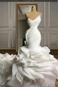 a white wedding dress on display in front of a mirror