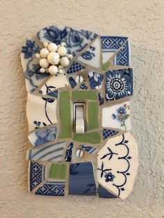 a decorative light switch plate with blue and green tiles on it's cover, next to a white flower