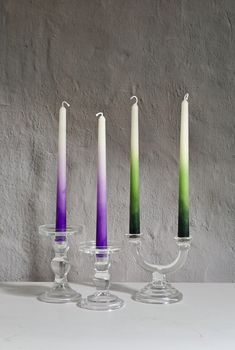 three candles are sitting in glass holders with one candle on the other side and another between them