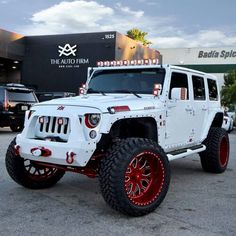 a white jeep with red rims parked in front of a building