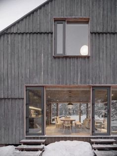 the outside of a house with snow on the ground and wooden steps leading up to it