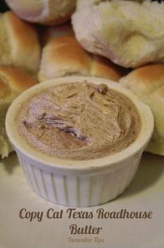 a close up of a bowl of food on a plate with rolls in the background