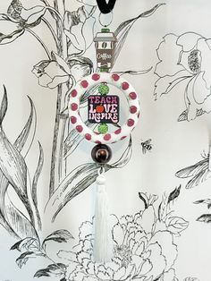 a keychain hanging from the side of a wall with flowers and a bird on it