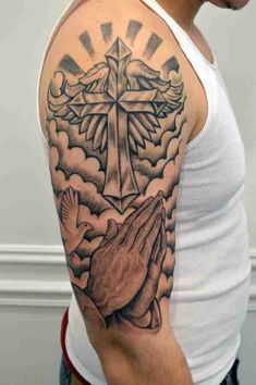 a man with a cross and praying hands tattoo on his upper arm, in front of clouds