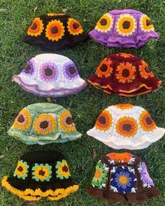 six crocheted hats are laying on the grass, all in different colors and patterns