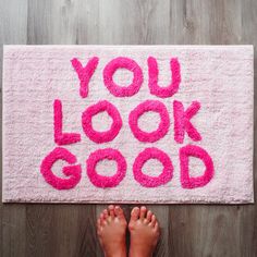 a pink rug with the words you look good written on it and two pairs of feet