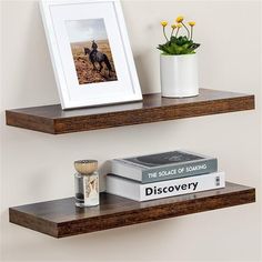 two wooden shelves holding books and a vase with flowers on them, along with a framed photograph