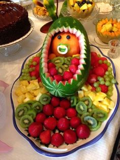 there is a plate that has fruit in the shape of a face on it and other fruits around it