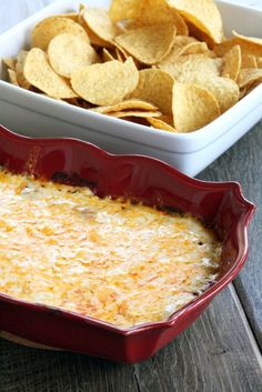 a casserole dish filled with cheese and tortilla chips on a wooden table