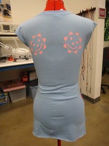 the back of a woman's blue shirt with pink smiley faces on it in a shop