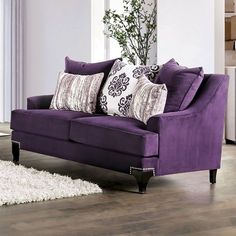 a purple couch sitting on top of a hard wood floor next to a white rug