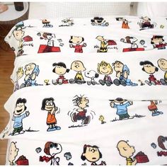 a bed with peanuts on it and other cartoon characters printed on the sheet coverlet