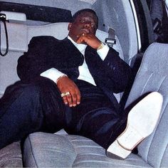 a man sitting in the back seat of a car with his hand on his chin