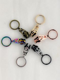 six different colored metal key chains on a white surface