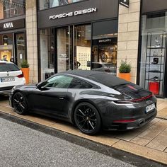 a black porsche parked on the side of a street in front of a storefront