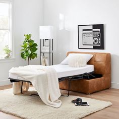 a bed sitting on top of a wooden floor next to a white rug and window