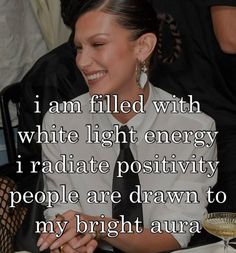 a woman sitting at a table in front of a wine glass with the caption i am filled with white light energy i radiate positivity people are drawn to my bright aura