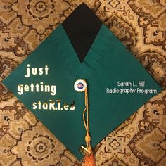 a green graduation cap with the words just getting started on it and a tassel