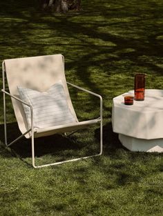 two chairs sitting on top of a lush green field next to a table covered in a white cloth