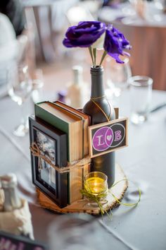 the table is set with books, wine glasses and purple flowers in a vase on top