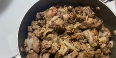 meat and onions cooking in a pan on the stove