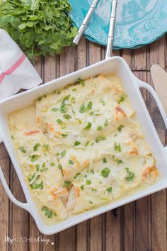 a casserole dish with chicken and cheese in it on a wooden table next to parsley