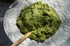 a white plate topped with green food and a wooden spoon