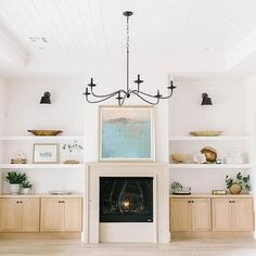 a living room filled with furniture and a fire place under a chandelier hanging from the ceiling