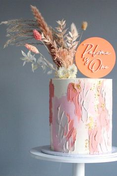 there is a pink and white cake with flowers on the top it has an orange sign that says please to go