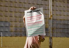 a person holding up a piece of paper with writing on it in front of a brick wall