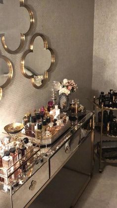 a mirrored table topped with lots of bottles next to a wall mounted mirror and two mirrors