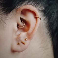 a person with two gold ear piercings on their ears