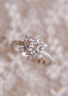 a diamond ring sitting on top of a lace covered surface