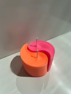 an orange and pink candle sitting on top of a white table