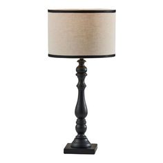 a black lamp with a beige shade on the base and a white lampshade